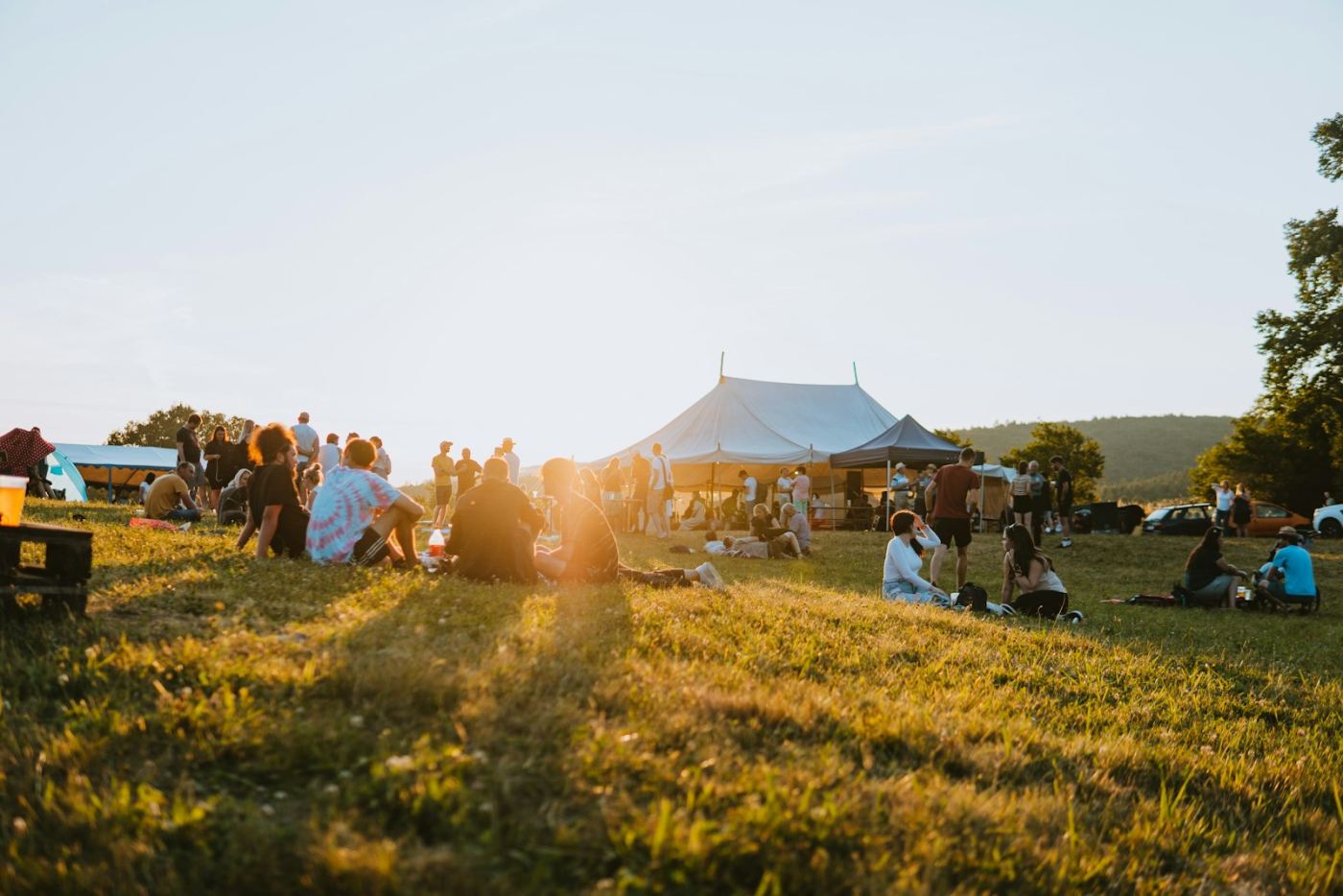 A festival meadow with a white tent in golden light